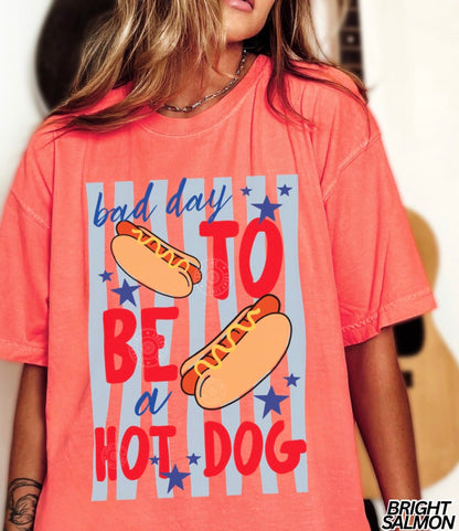 Person wearing a coral t-shirt with hot dog graphic and text
