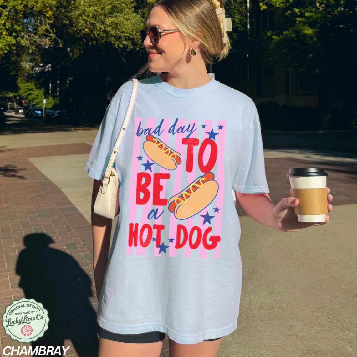 Woman wearing a t-shirt with a humorous graphic and text, holding a coffee cup outdoors.