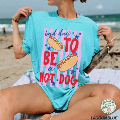 Person wearing a light blue t-shirt with a colorful graphic and text on a beach.