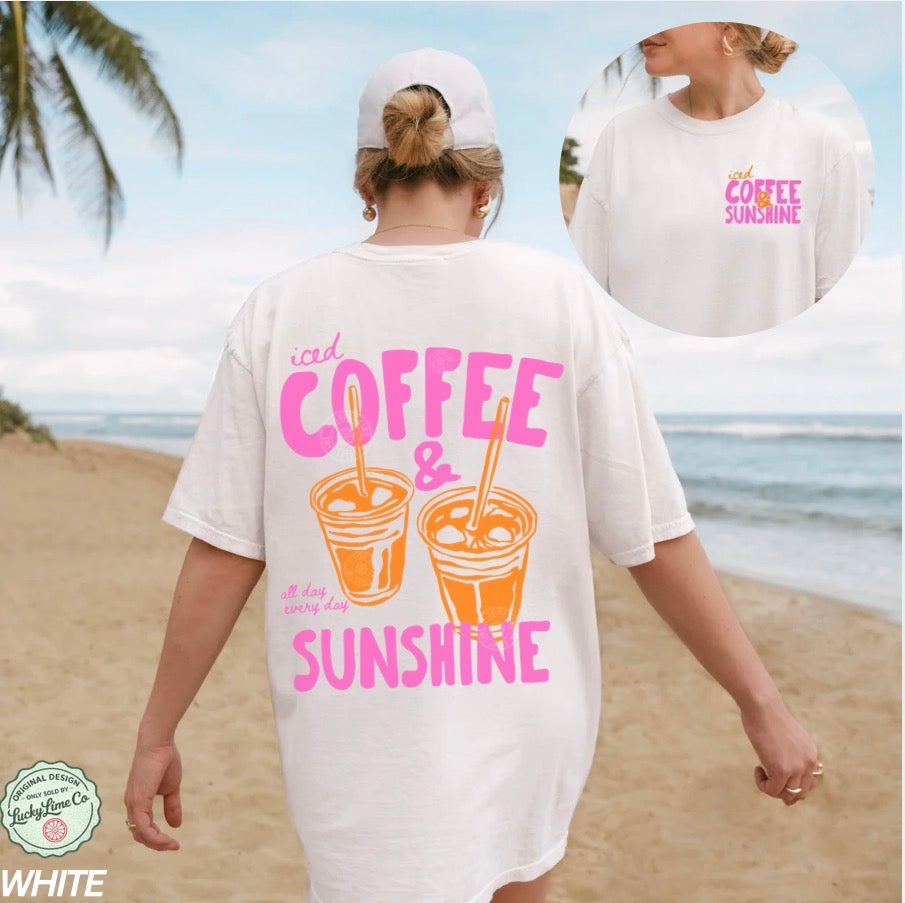 Woman wearing a white t-shirt with 'iced coffee & sunshine' design on a beach.