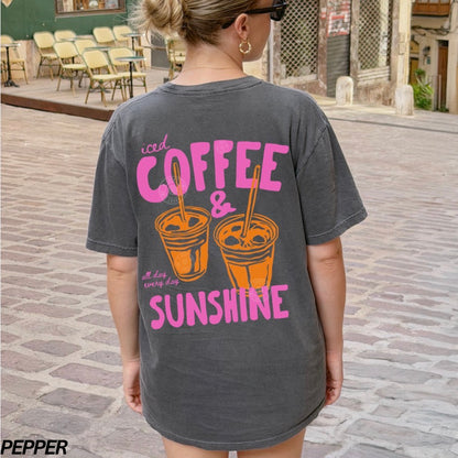 Person wearing a t-shirt with 'iced coffee & sunshine' text on a street.