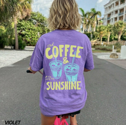 Person wearing a purple t-shirt with 'iced coffee & sunshine' text, standing outdoors.
