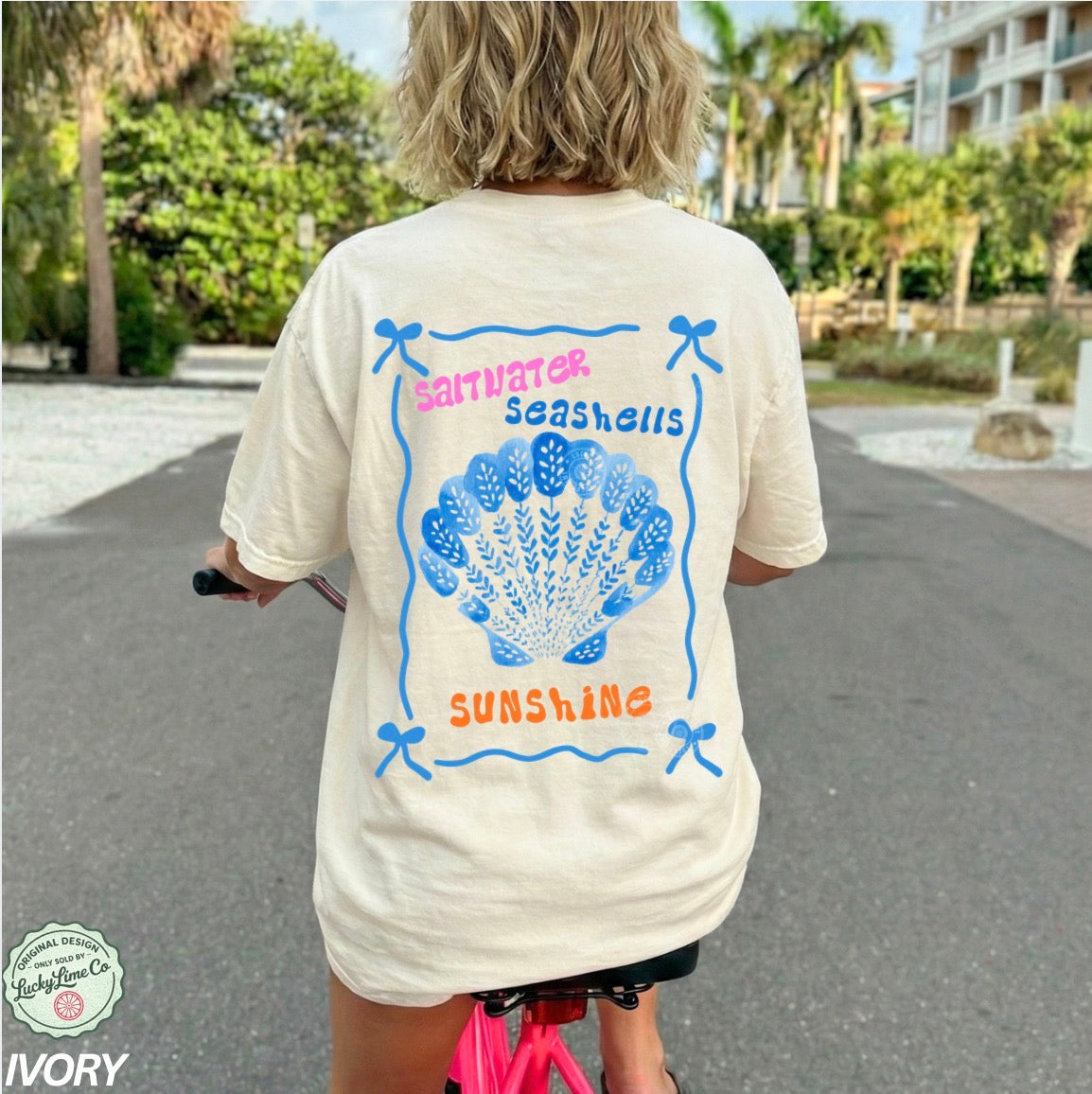 Person wearing a t-shirt with a shell design and text in an outdoor setting