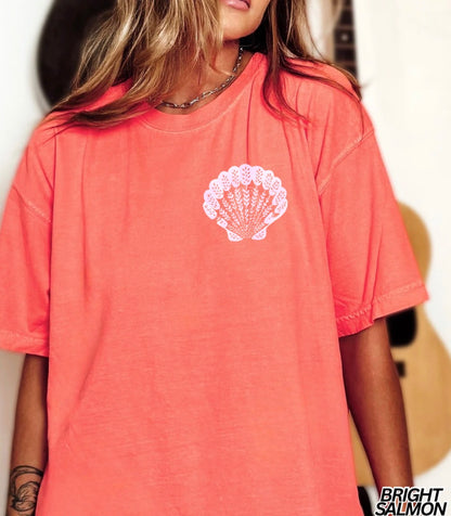Person wearing a bright salmon-colored t-shirt with a white shell design.