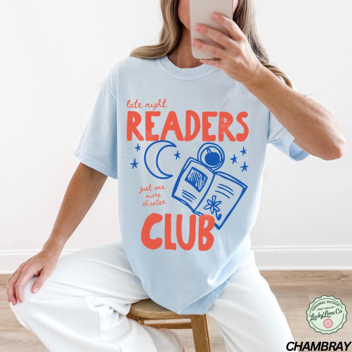 Person wearing a light blue t-shirt with 'late night READERS CLUB' text and graphics.