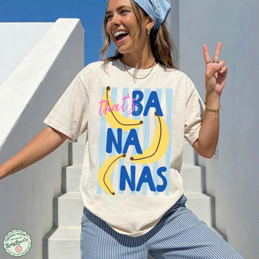 Woman wearing an ivory  t-shirt with banana graphic and text on a white staircase.