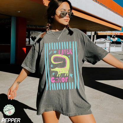 Woman wearing a gray oversized t-shirt with a colorful graphic design in an urban setting.