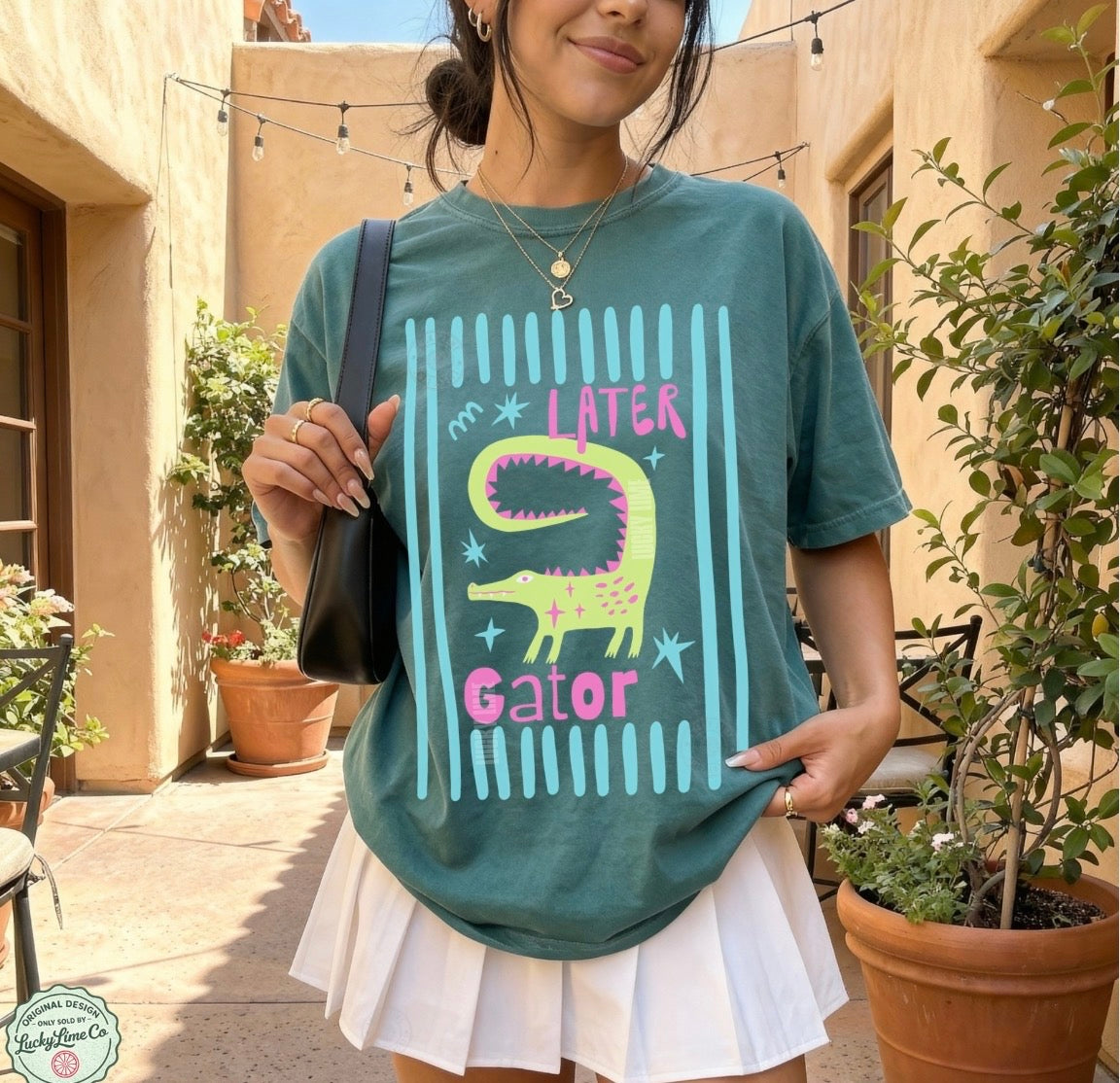 Girl wearing blue spruce colored shirt with “later gator” and alligator graphic