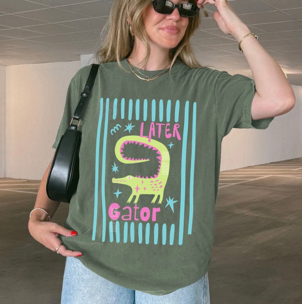 Girl wearing moss colored shirt with “later gator” and alligator graphic