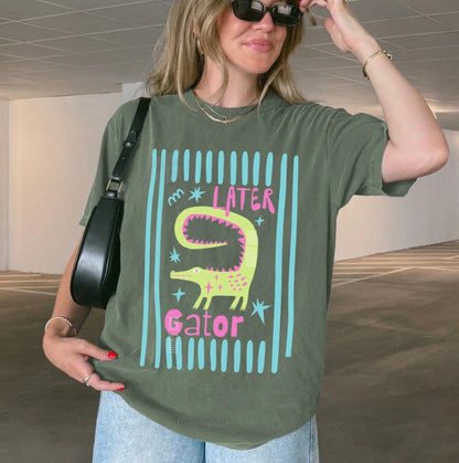 Girl wearing moss colored shirt with “later gator” and alligator graphic