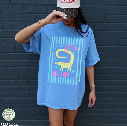 Girl wearing flo blue colored shirt with “later gator” and alligator graphic