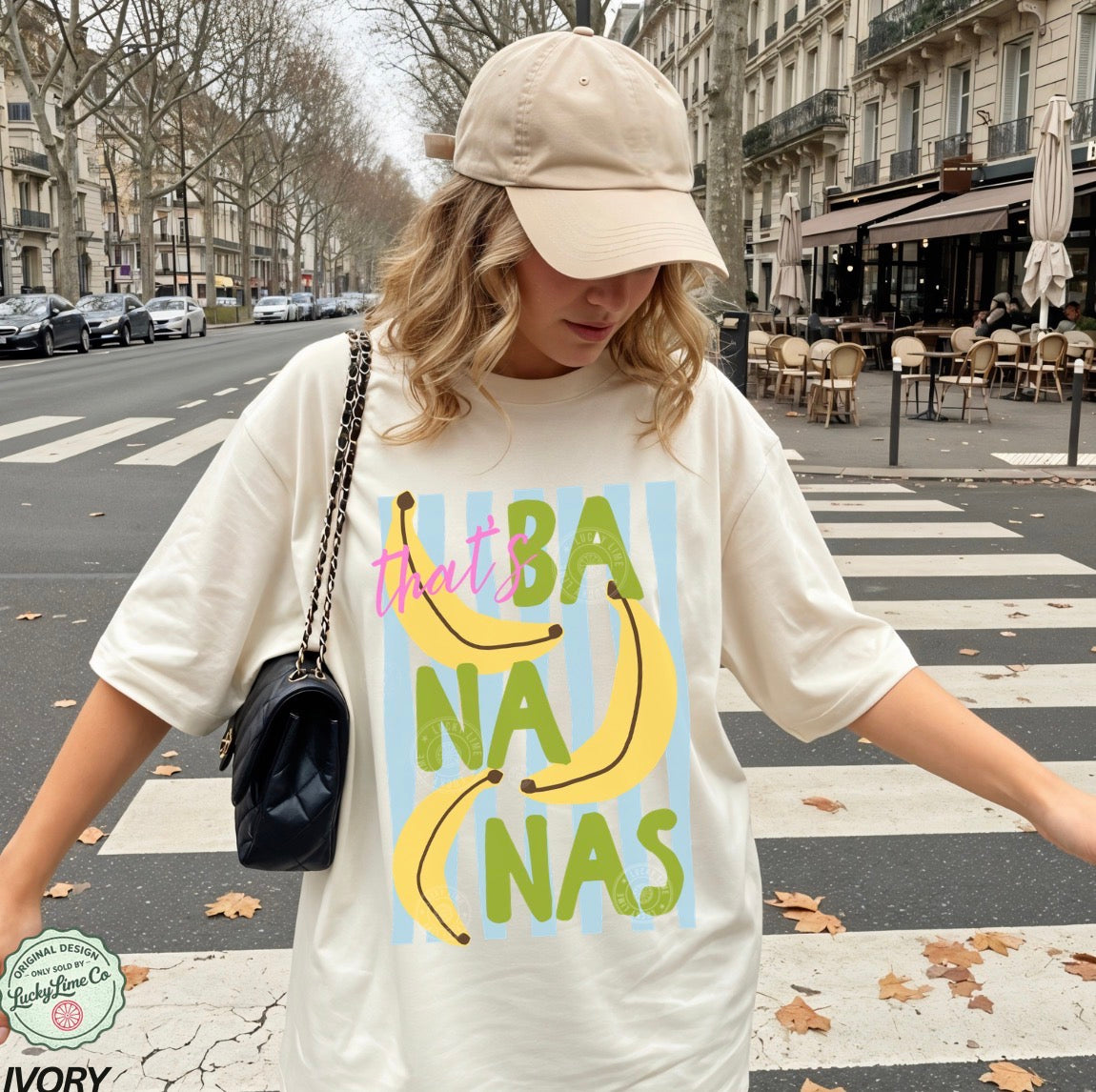 Girl wearing an ivory shirt that says “that’s bananas” standing on a street