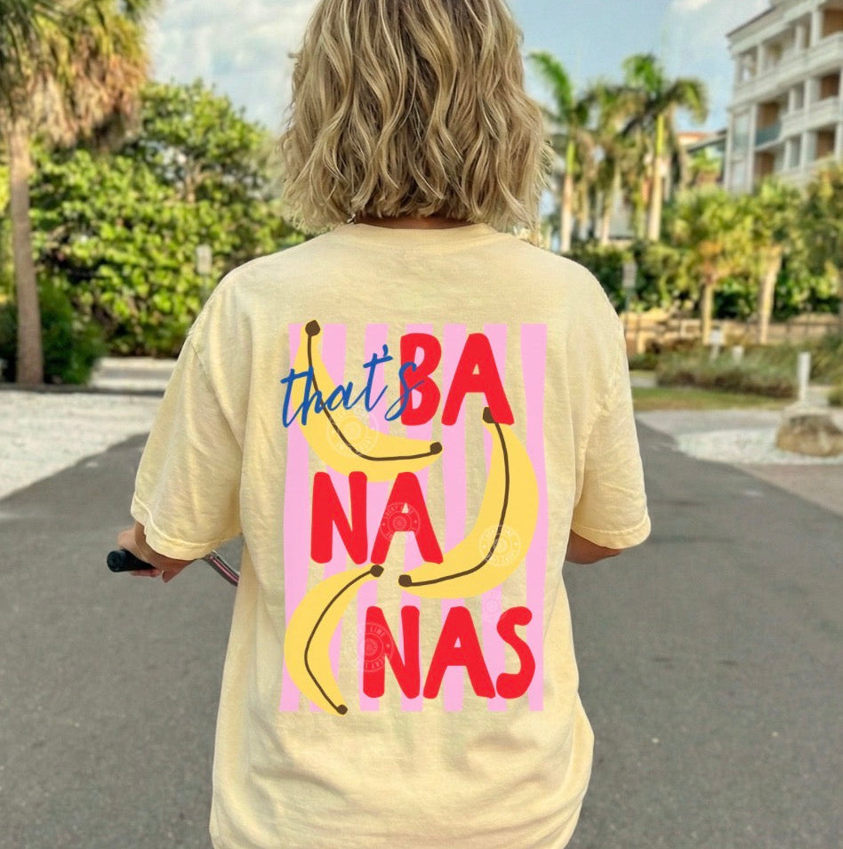 Person wearing a yellow t-shirt with 'that's bananas' design, riding a bike outdoors.