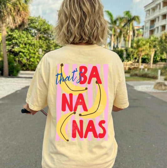 Person wearing a yellow t-shirt with 'that's bananas' design, riding a bike outdoors.