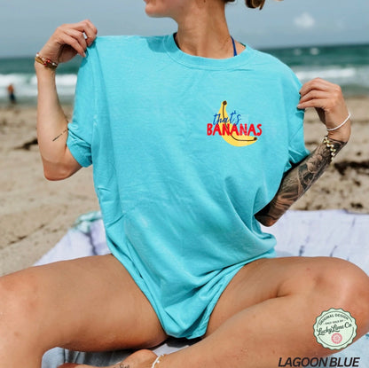 Person wearing a light blue t-shirt with 'That's Bananas' text on a beach.