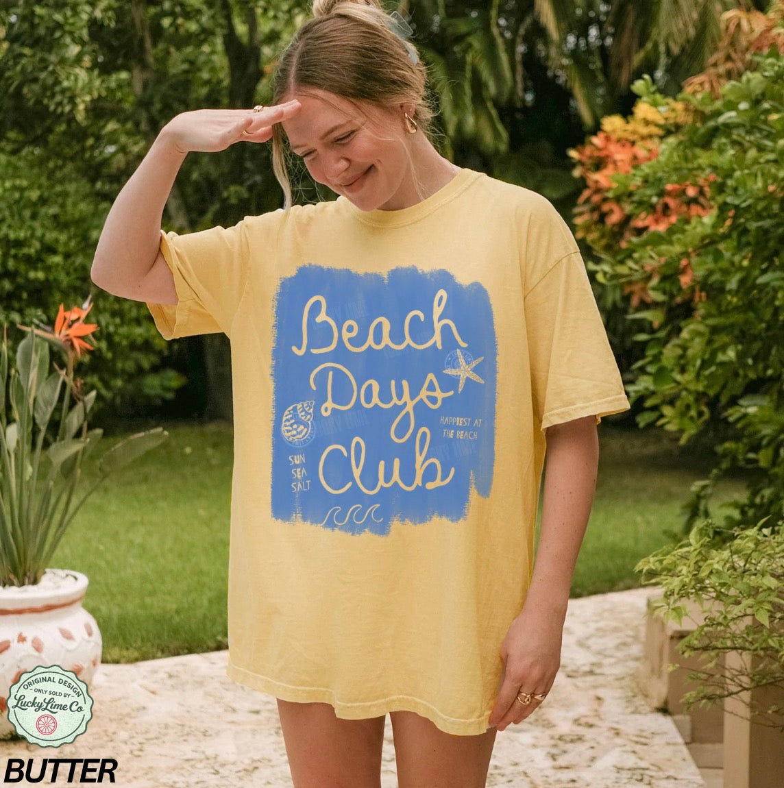 Woman wearing a yellow t-shirt with 'Beach Days Club' design outdoors.