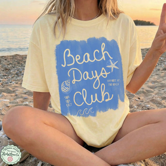 Person wearing a 'Beach Days Club' t-shirt on a beach