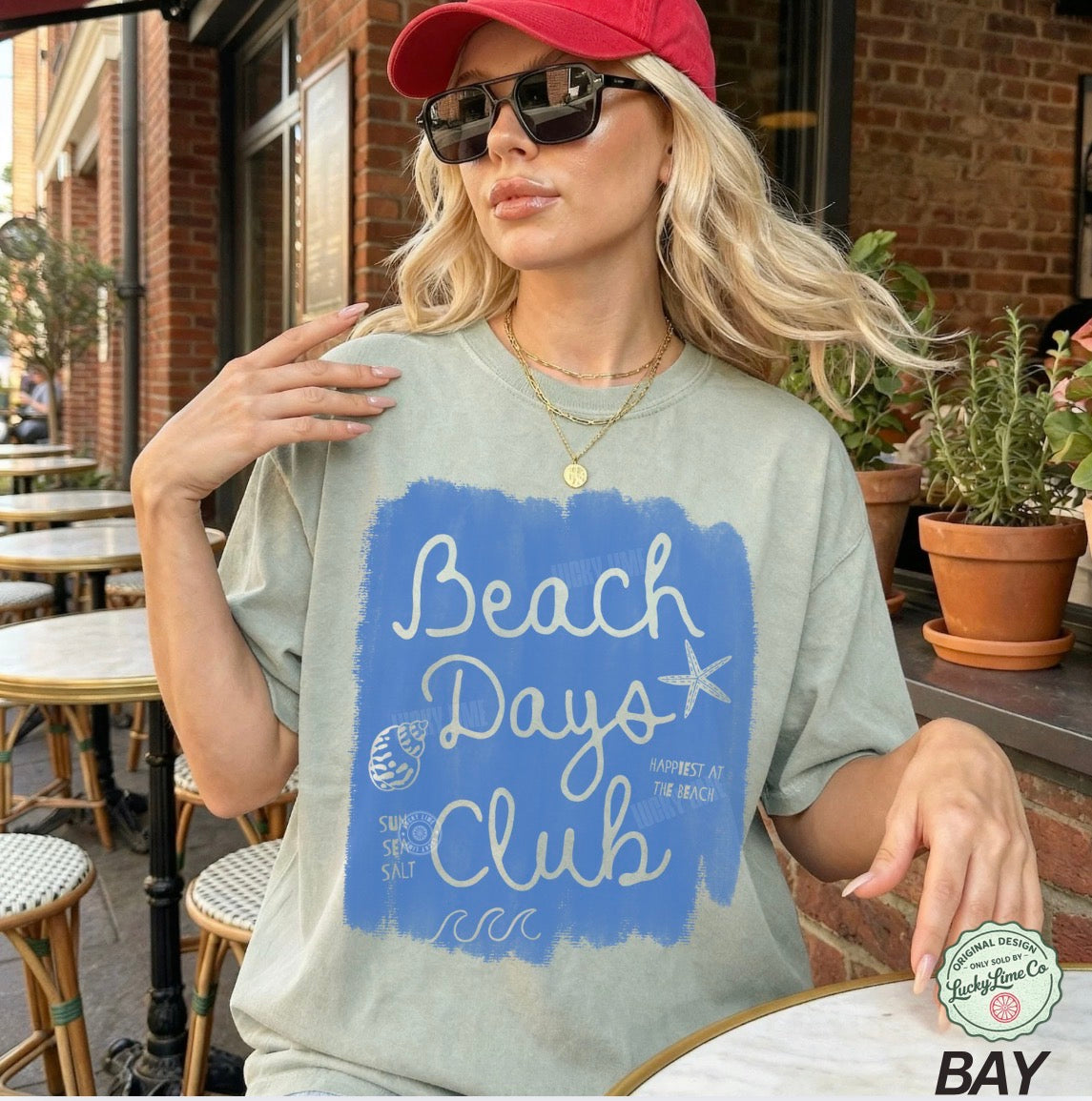 Woman wearing a 'Beach Days Club' t-shirt in an outdoor setting.