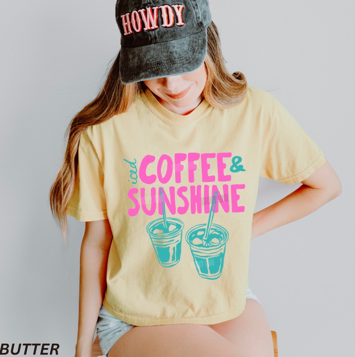 Person wearing a yellow t-shirt with 'Coffee & Sunshine' text and a cap with 'HOWDY' text.