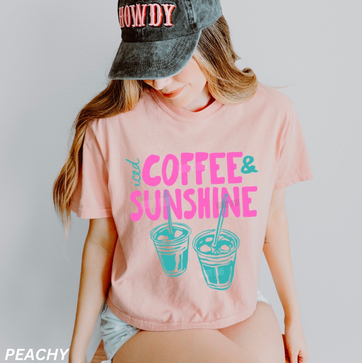 Person wearing a pink t-shirt with 'Coffee & Sunshine' text and graphics, paired with a cap.
