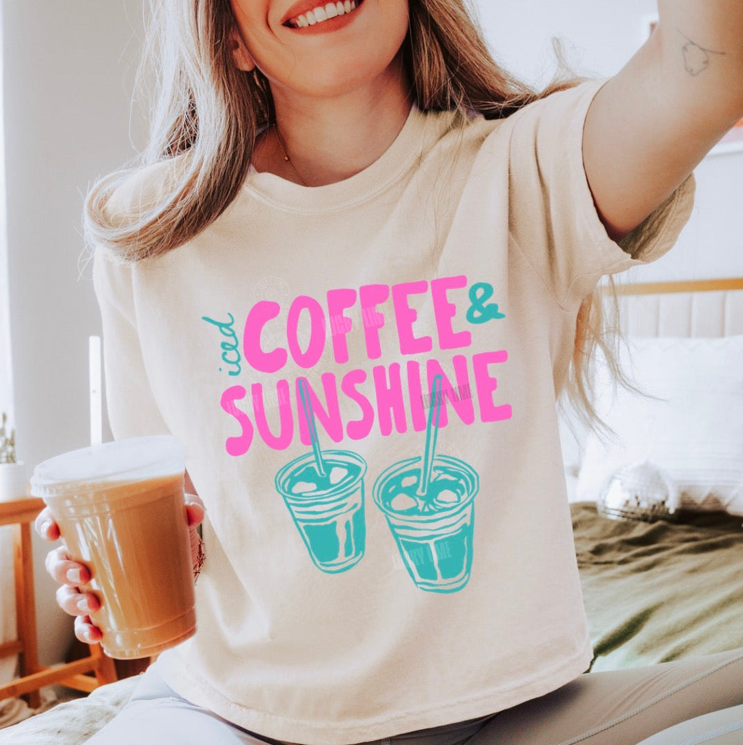 Person wearing a t-shirt with 'Coffee & Sunshine' design, holding a coffee cup.