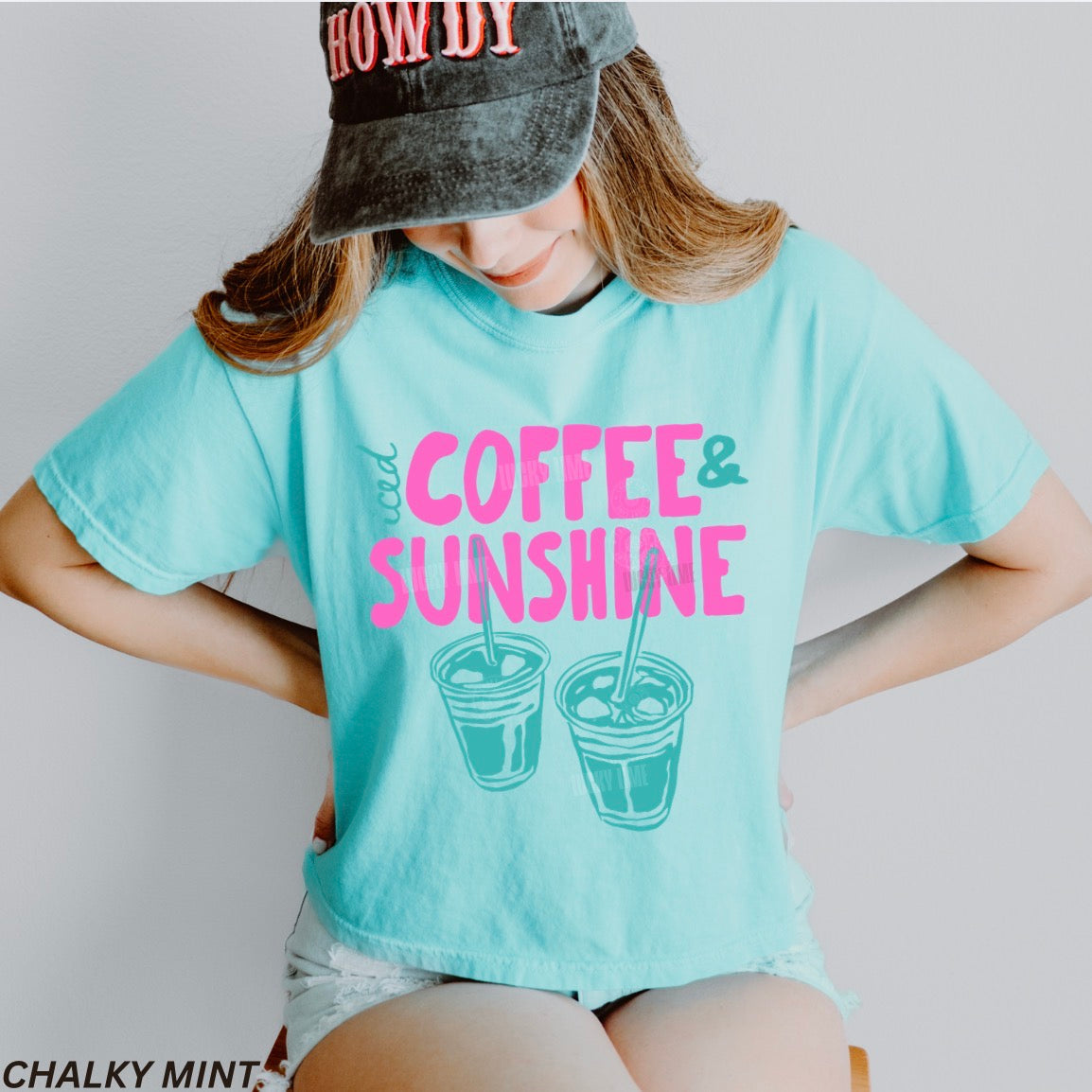 Person wearing a light blue t-shirt with 'Coffee & Sunshine' text and graphics, standing against a plain background.