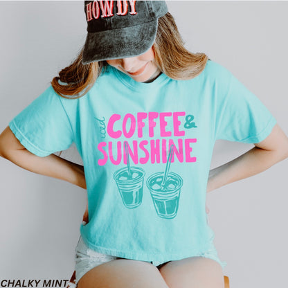 Person wearing a light blue t-shirt with 'Coffee & Sunshine' text and graphics, standing against a plain background.