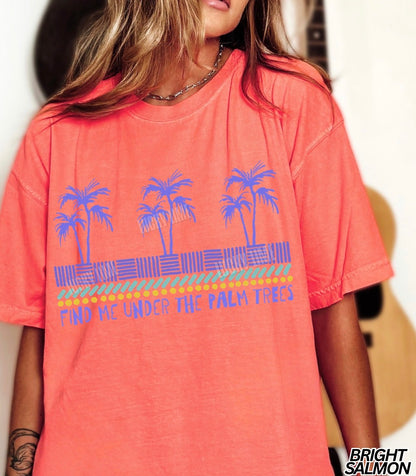 Person wearing a bright salmon t-shirt with palm tree design and text.