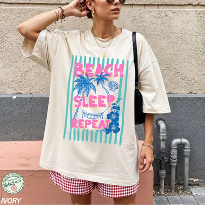 Person wearing a white t-shirt with 'Beach Sleep Repeat' design and checkered shorts, standing against a wall.