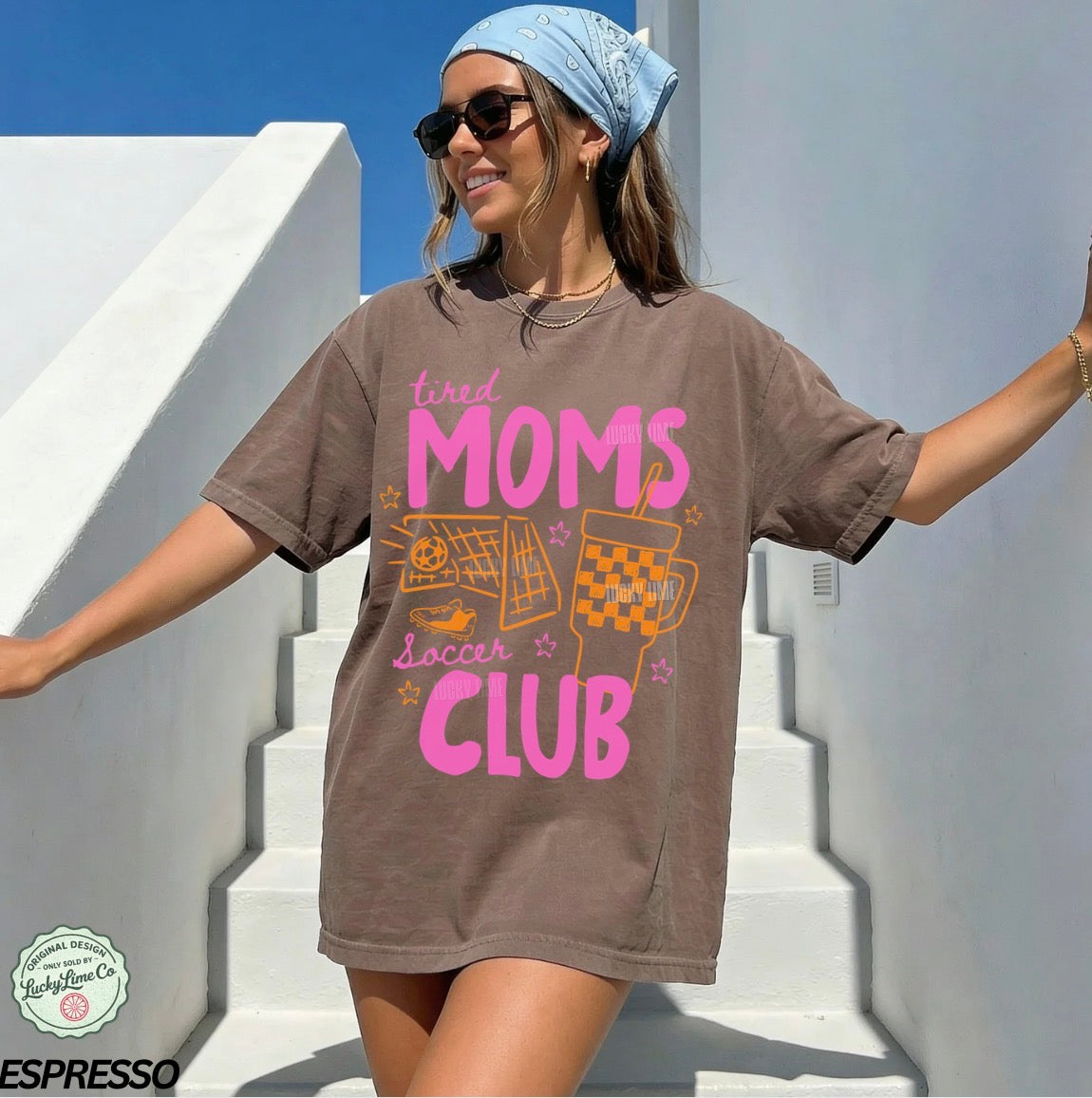Woman wearing a brown t-shirt with colorful text and graphics, standing on white steps.