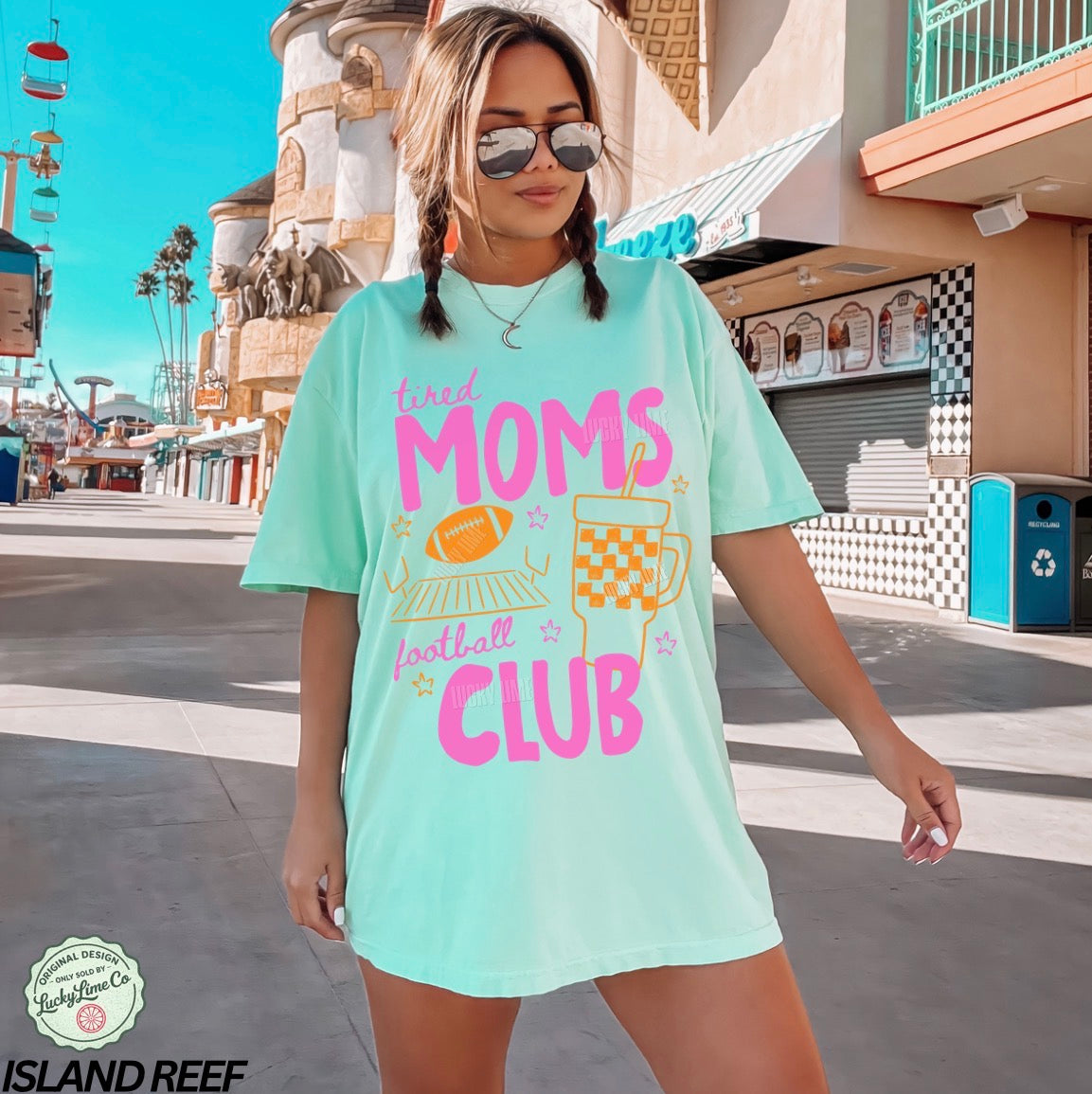 Woman wearing a light blue t-shirt with 'tired moms football club' text in a casual setting.
