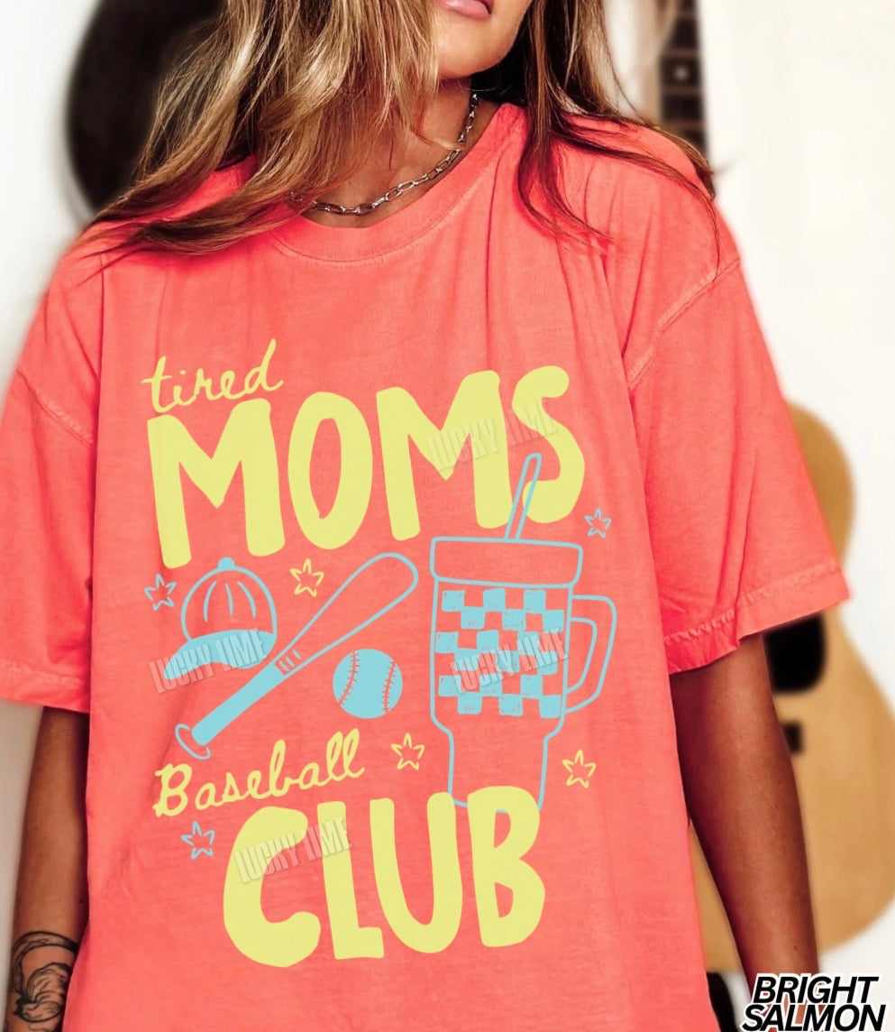 Person wearing a coral t-shirt with 'tired moms baseball club' text and graphics.