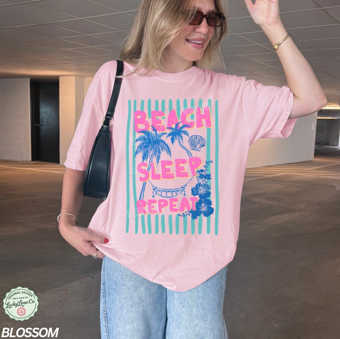 Woman wearing a pink t-shirt with 'Beach Sleep Repeat' text and graphics, standing in an indoor setting.