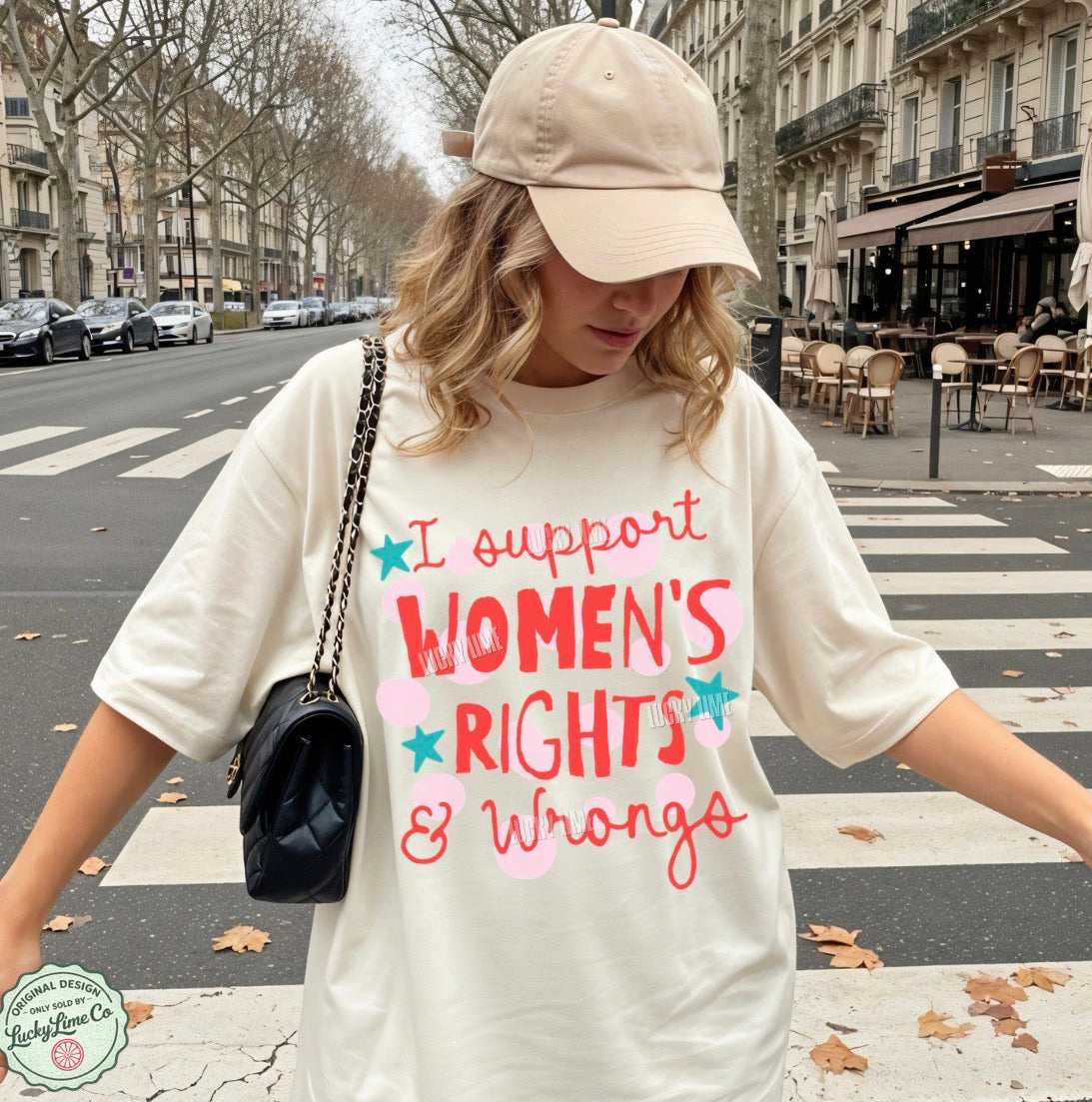 Person wearing a white t-shirt with 'I support women's rights & wrongs' text on a city street.