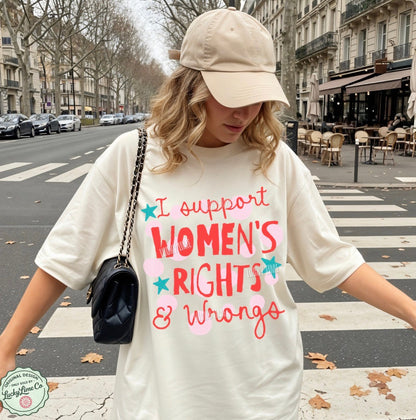 Person wearing a white t-shirt with 'I support women's rights & wrongs' text on a city street.