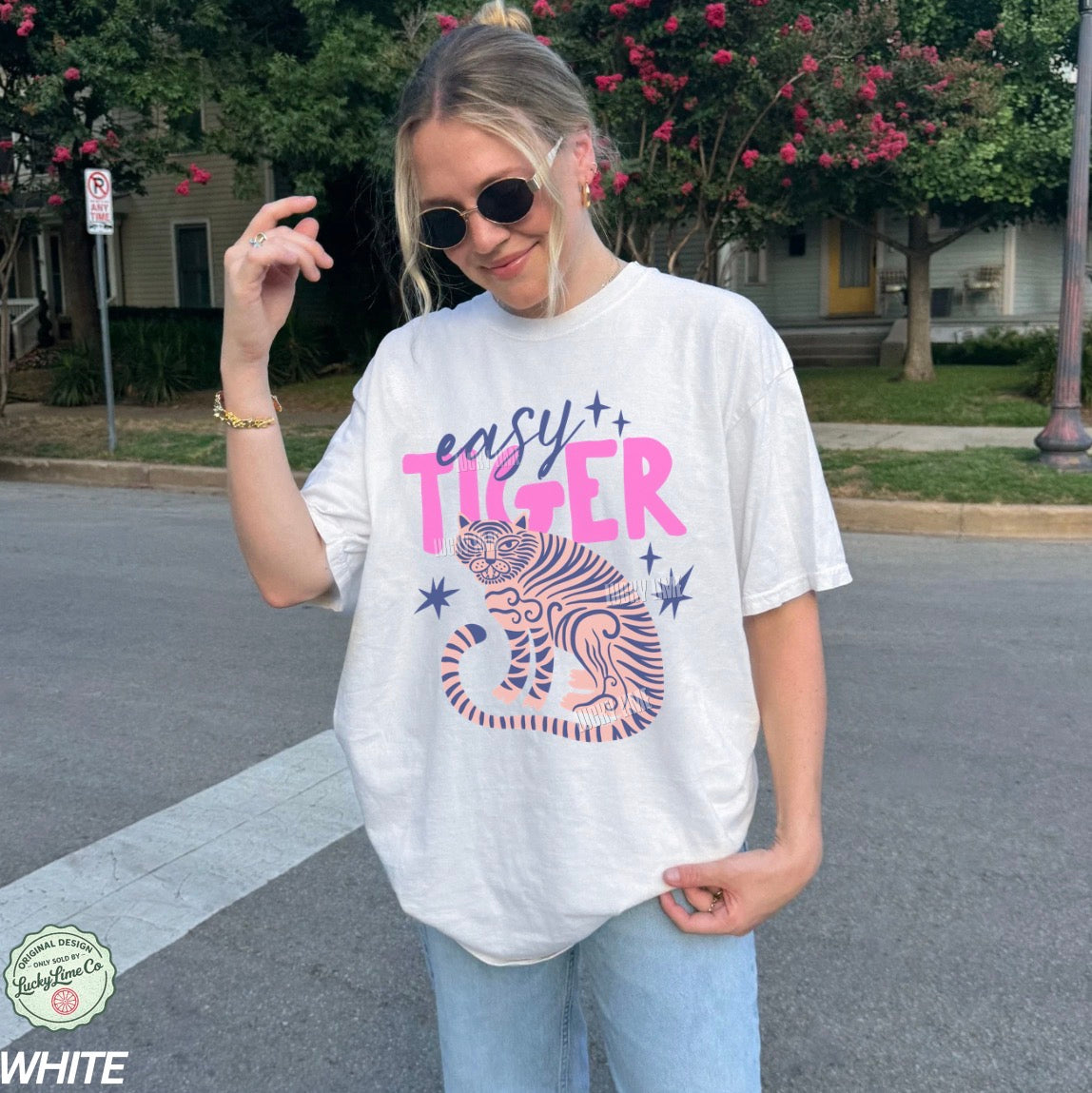 Person wearing a white t-shirt with 'easy tiger' graphic design outdoors.