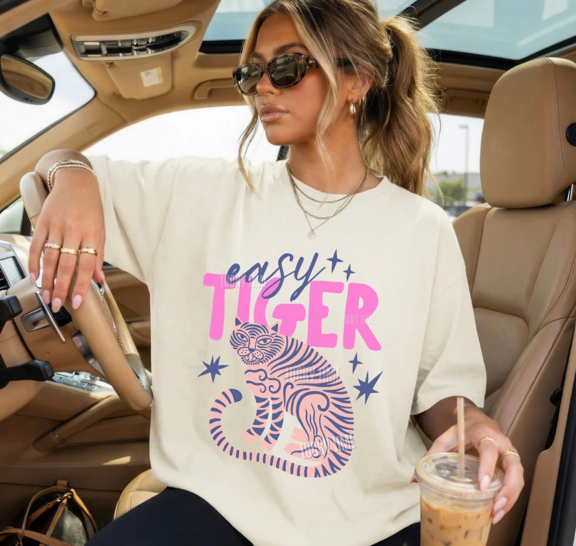 Woman sitting in a car wearing a 'easy tiger' t-shirt and holding a drink.