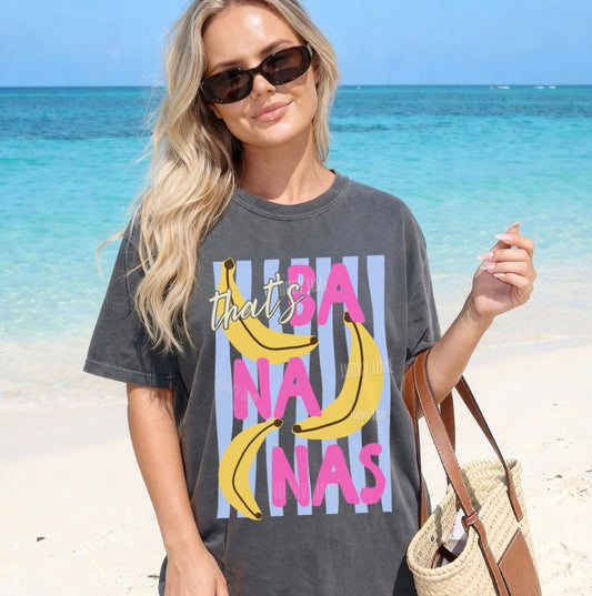 Woman wearing a graphic t-shirt with ' that’s BA NA NAs' design on a beach.