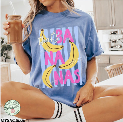 Person wearing a blue t-shirt with banana graphics and text, sitting in a kitchen.