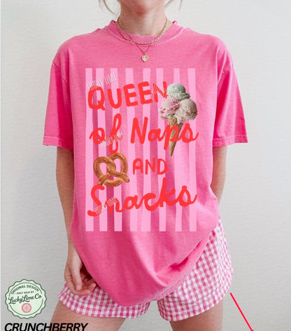 Person wearing a pink 'Queen of Naps and Snacks' t-shirt with ice cream graphic.
