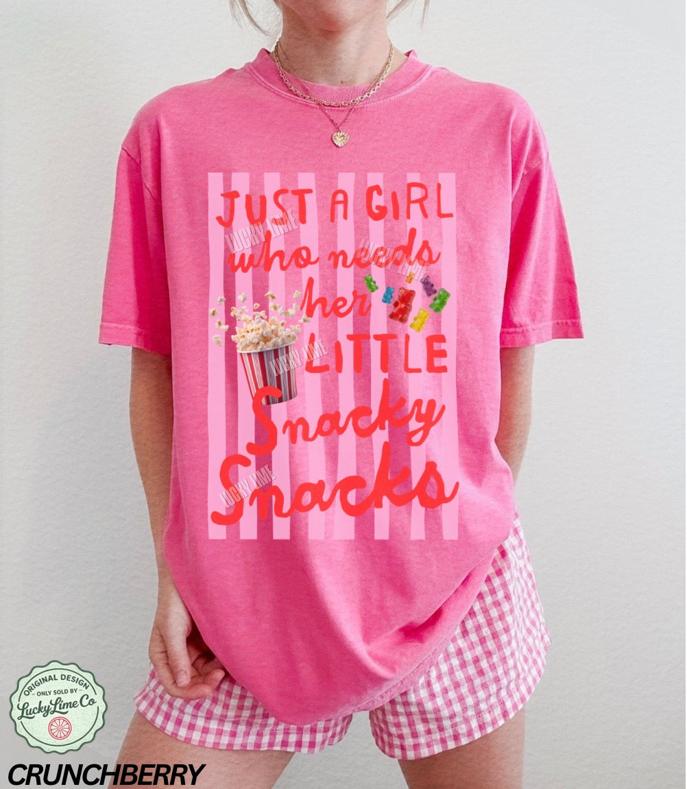 Person wearing a pink t-shirt with text and snacks graphics, standing against a plain background.