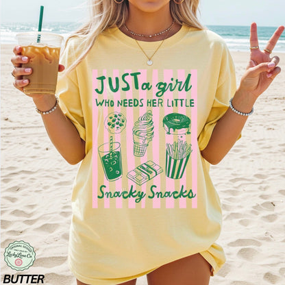 Person wearing a yellow t-shirt with a snack-themed design on a beach.