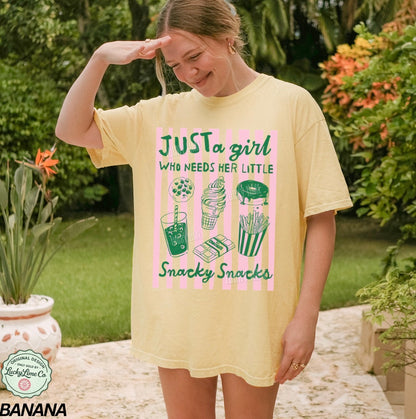 Woman wearing a yellow t-shirt with a graphic design and text, standing outdoors.