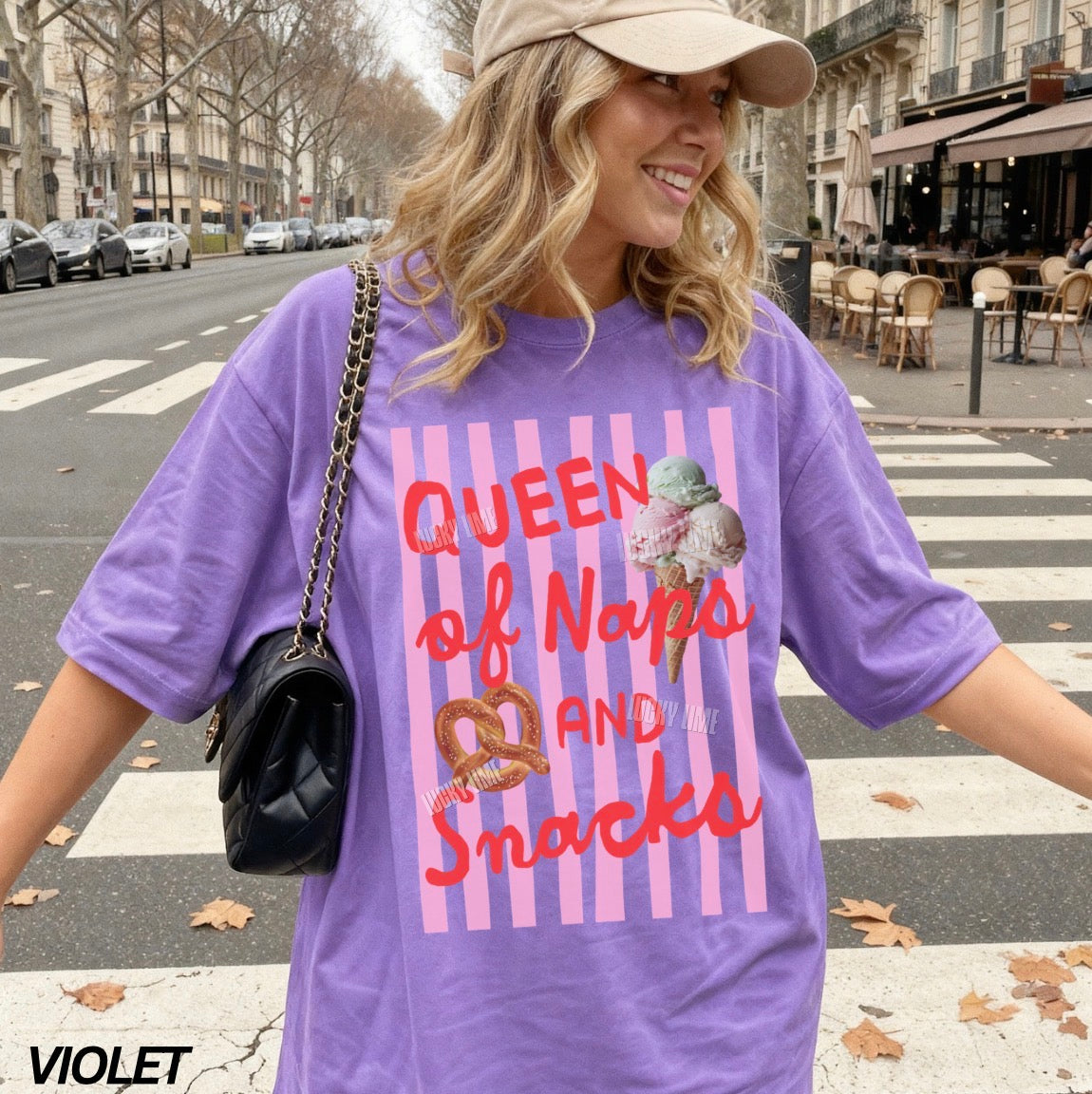 Woman wearing a purple t-shirt with a graphic design and text, standing on a street.