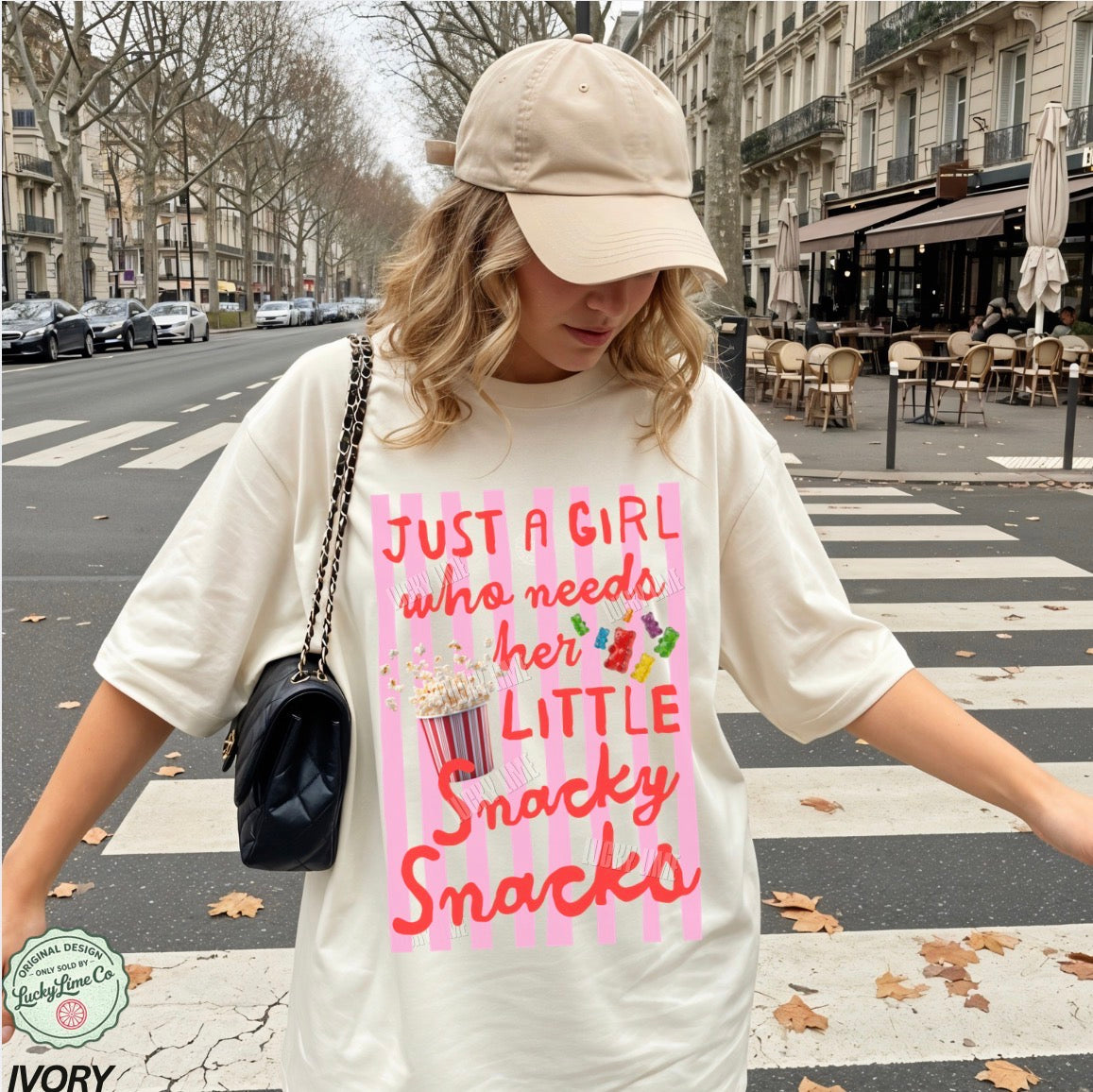 Woman wearing a white t-shirt with a colorful graphic and text, standing on a city street.