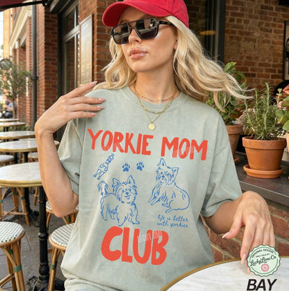 Woman wearing a 'Yorkie Mom Club' t-shirt outdoors.