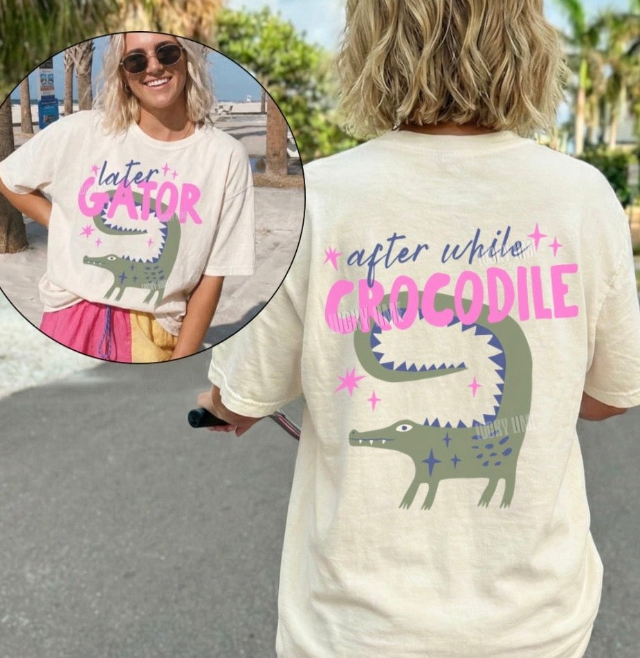 Person wearing a t-shirt with a crocodile graphic and text, standing outdoors.