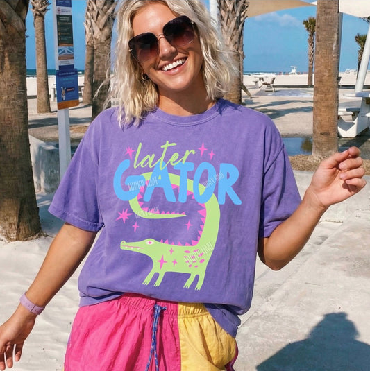Woman wearing a purple 'later GATOR' t-shirt at a beach.