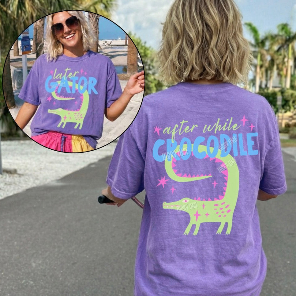 Person wearing a purple t-shirt with a crocodile graphic and text, standing outdoors.