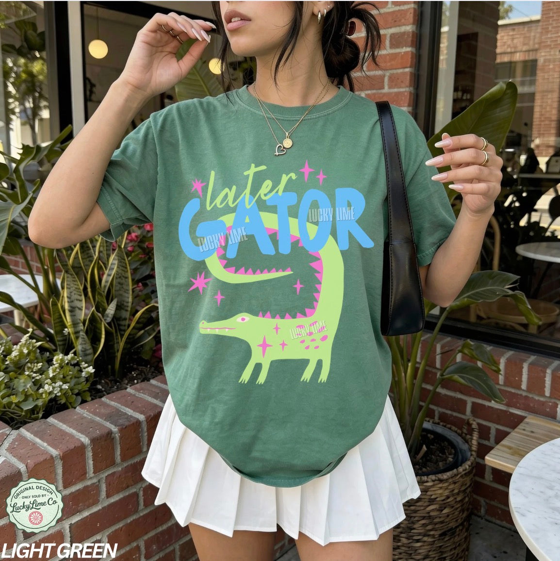 Person wearing a green t-shirt with 'later GATOR' design outdoors.